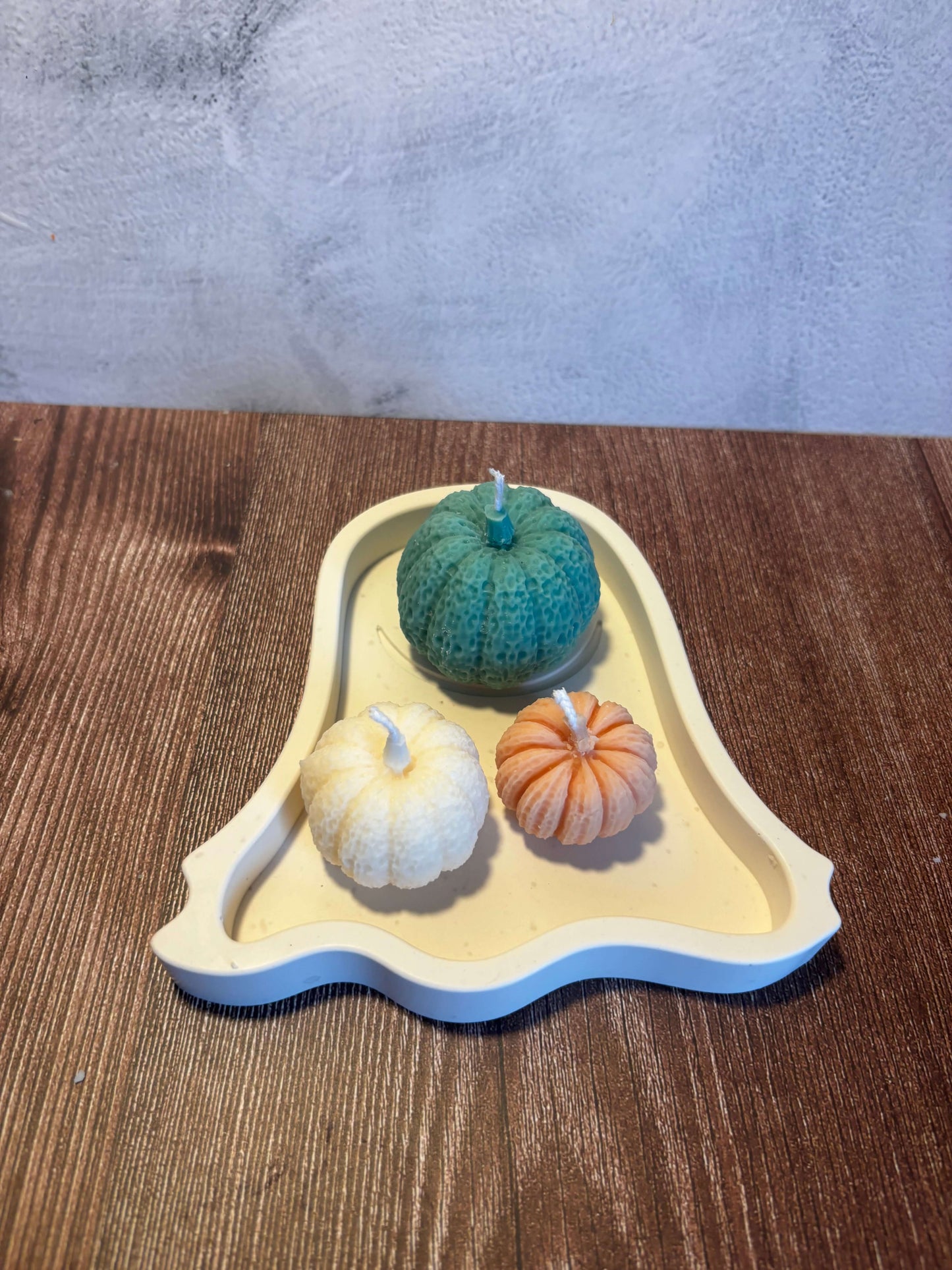 Decorative ghost tray with three small pumpkins on a wooden surface