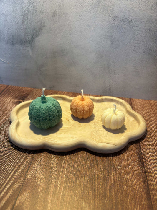 Three small pumpkins in different colors on a wooden surface