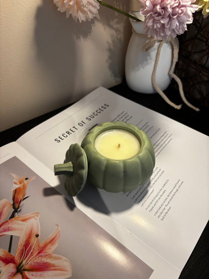 Green candle holder with a lit candle on an open book with floral illustrations