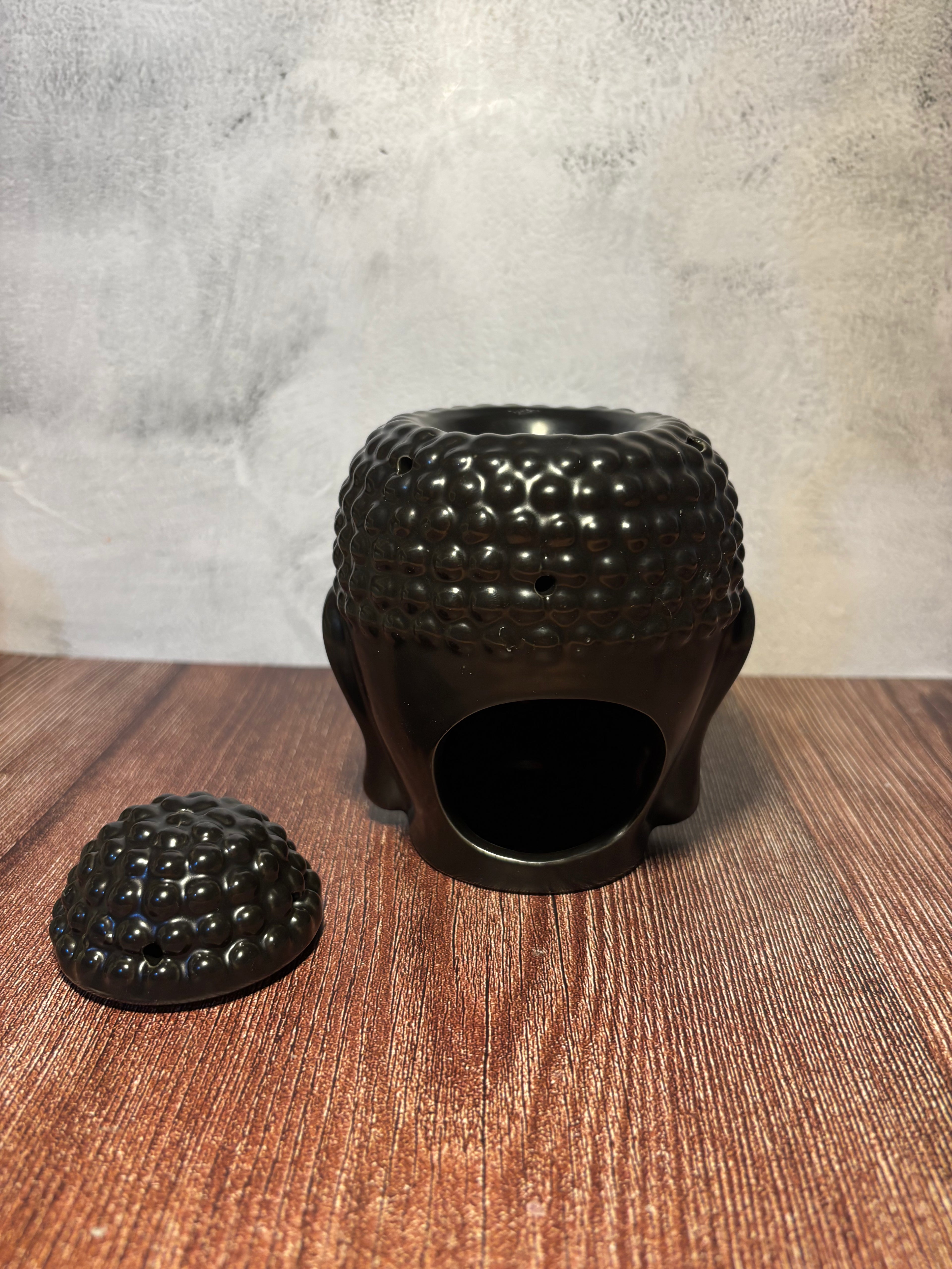 Black textured oil burner on a wooden surface with a neutral background