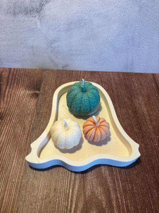 Decorative ghost tray with three small pumpkins on a wooden surface