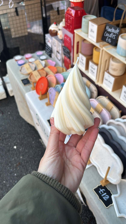 Hand holding a tree candle with a market stall in the background