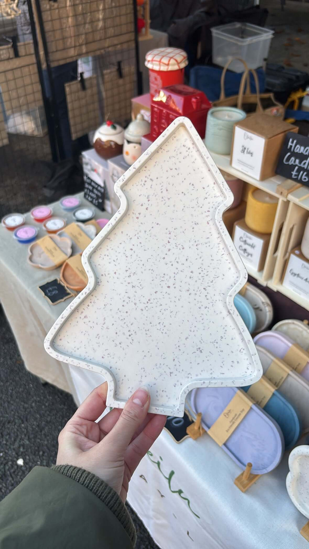 Handheld tree-shaped tray with a market stall in the background