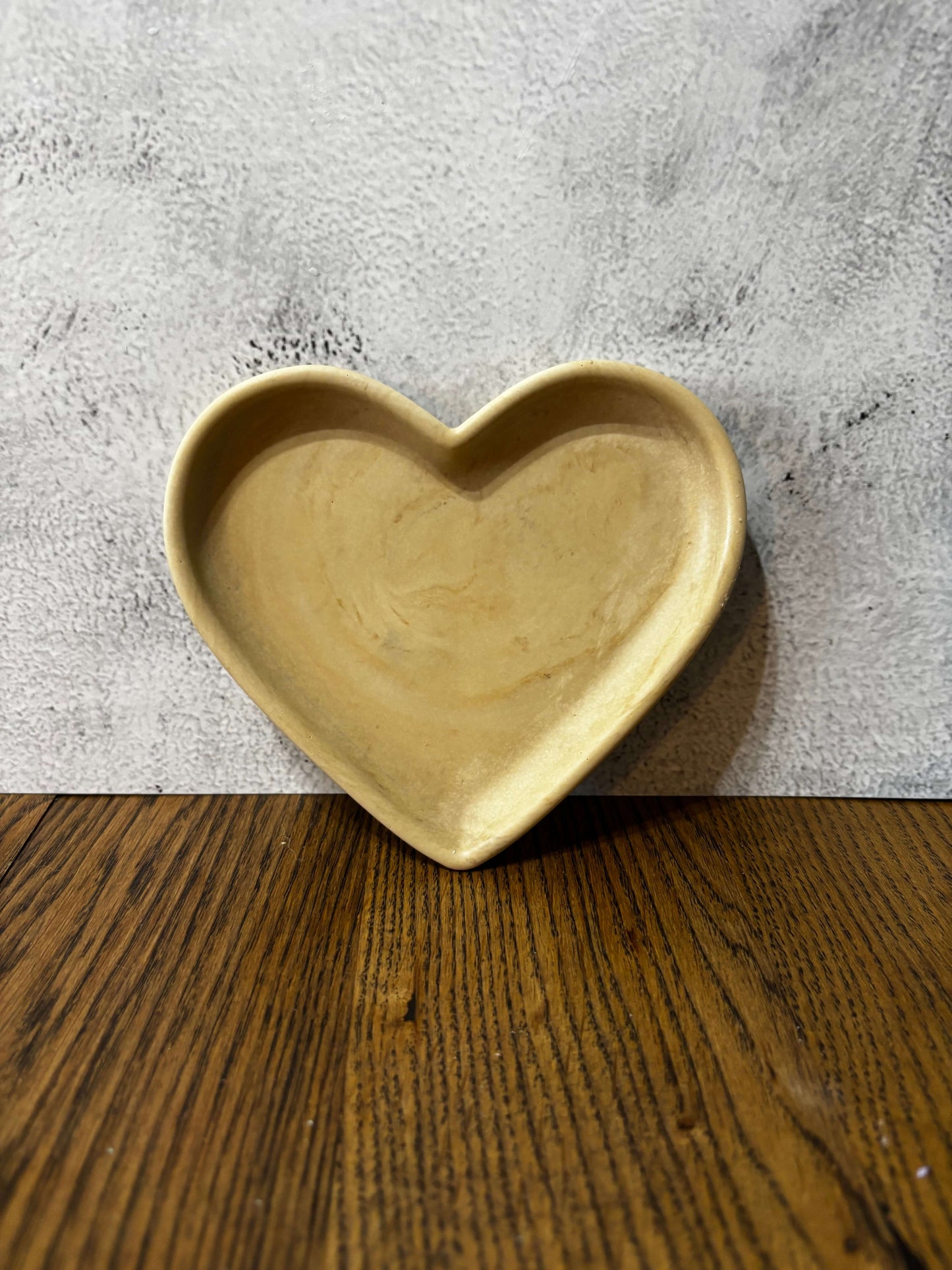 Heart-shaped ceramic dish on a textured surface with wooden background