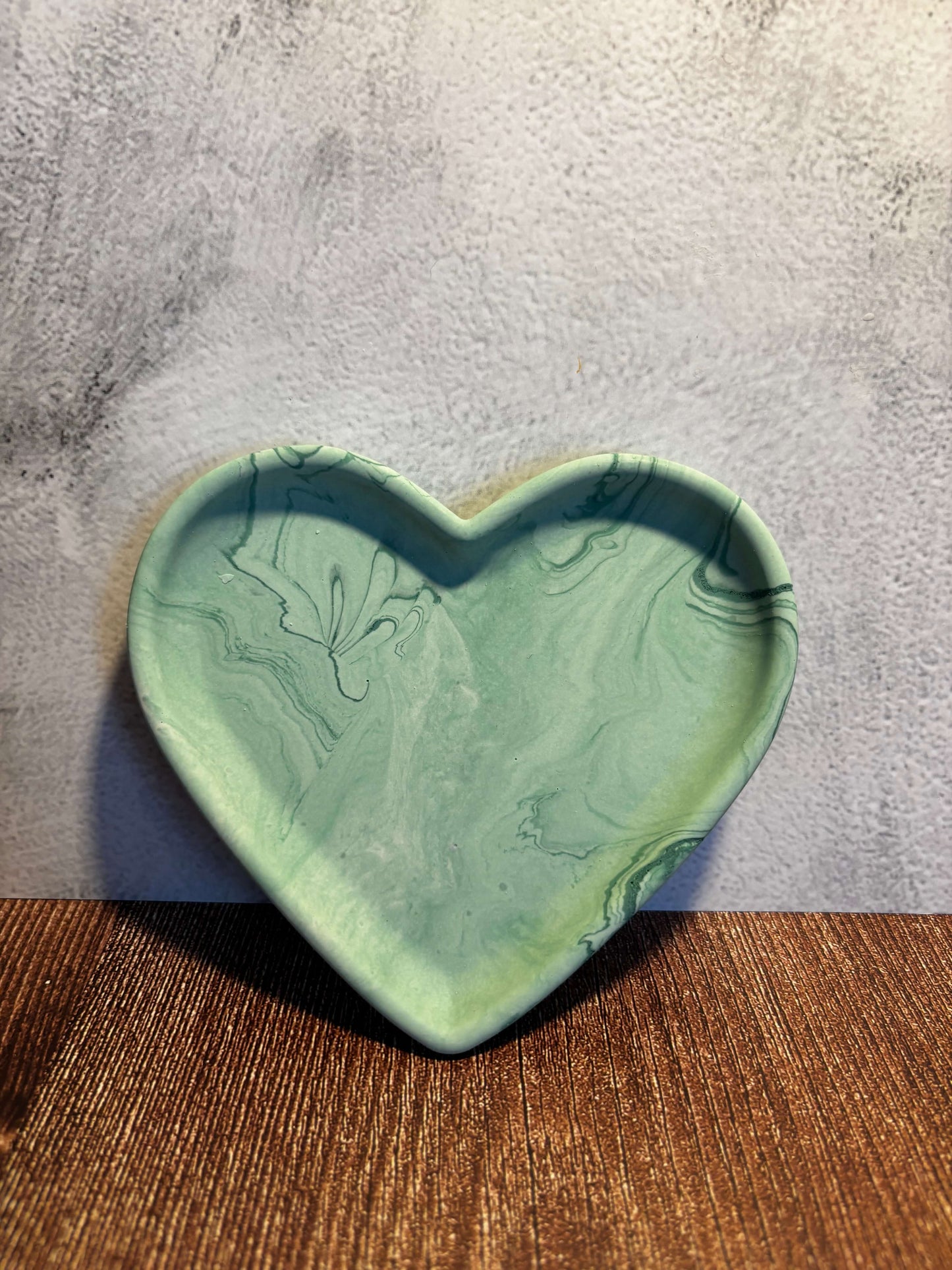 Heart-shaped green ceramic dish on a textured surface