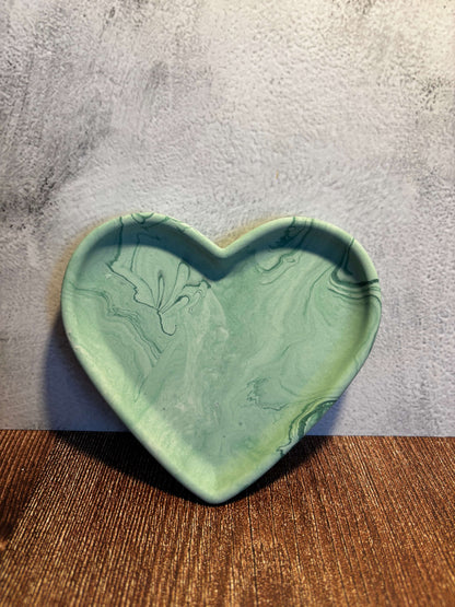 Heart-shaped green ceramic dish on a textured surface