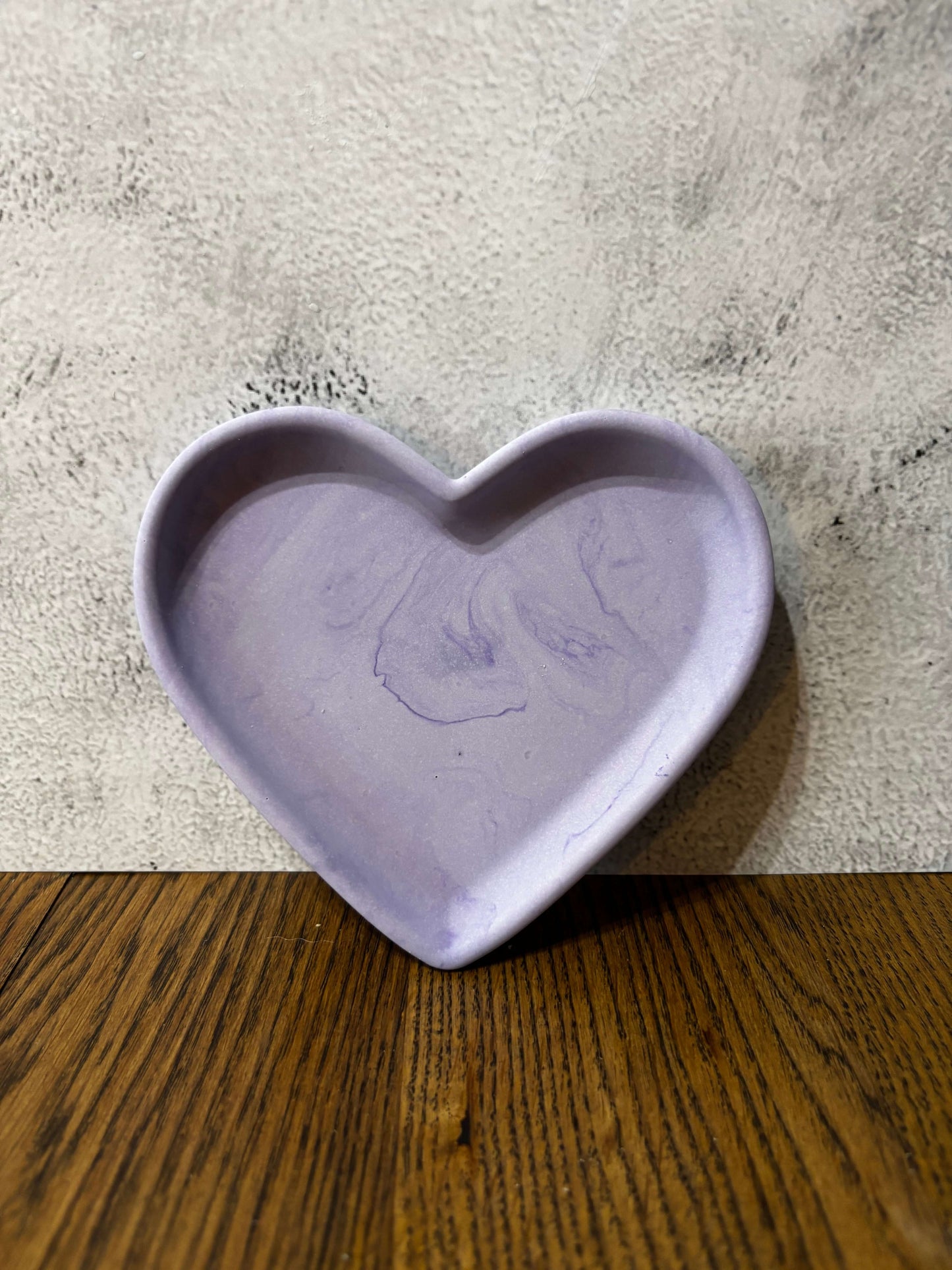 Heart-shaped purple object on a textured surface with wooden edge