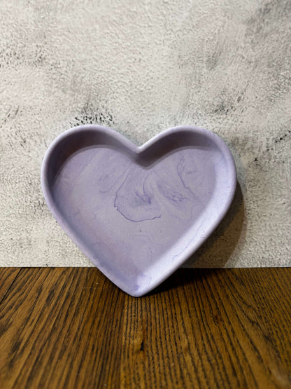 Heart-shaped purple object on a textured surface with wooden edge