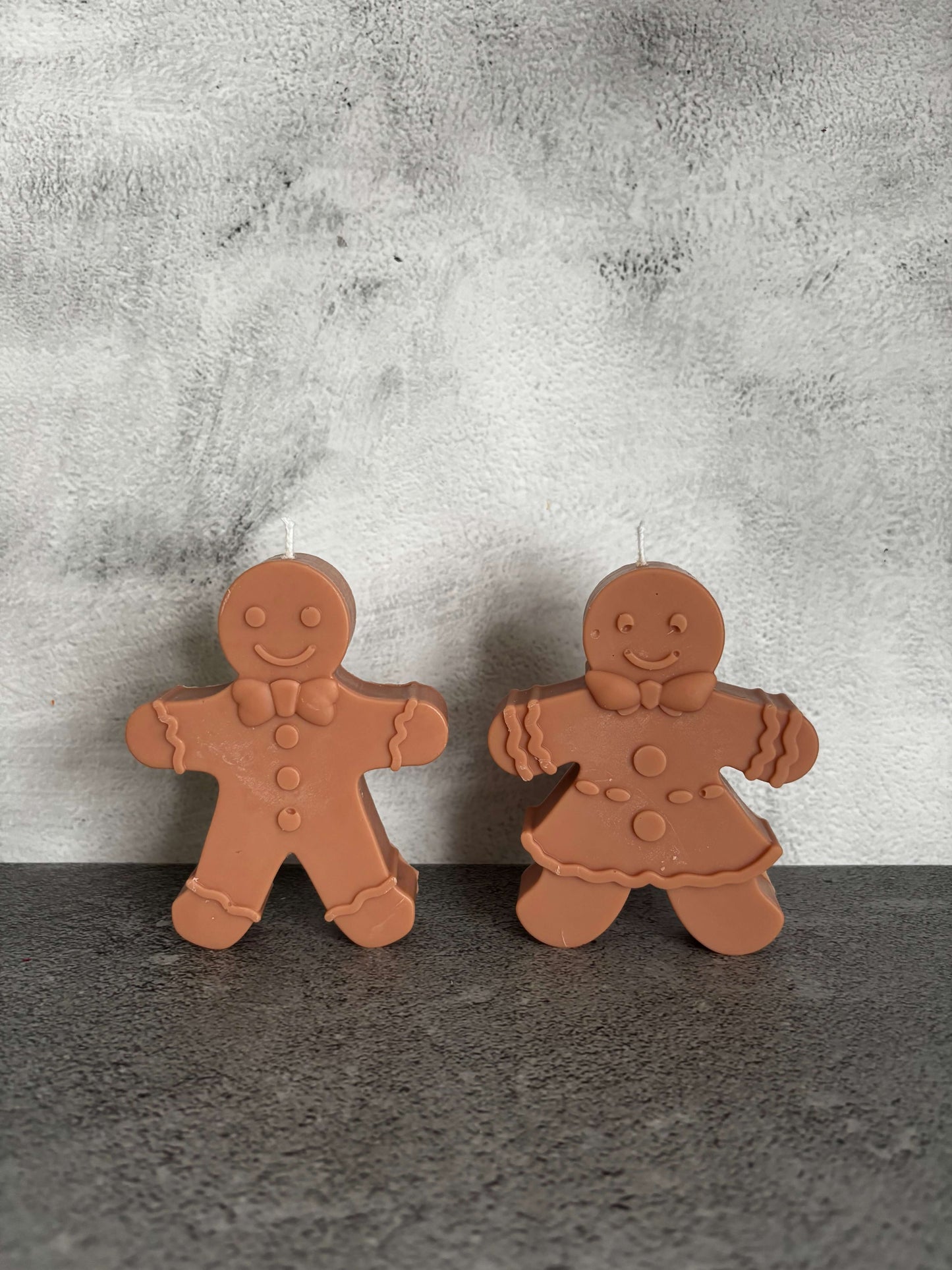Two gingerbread-shaped cookies on a textured surface