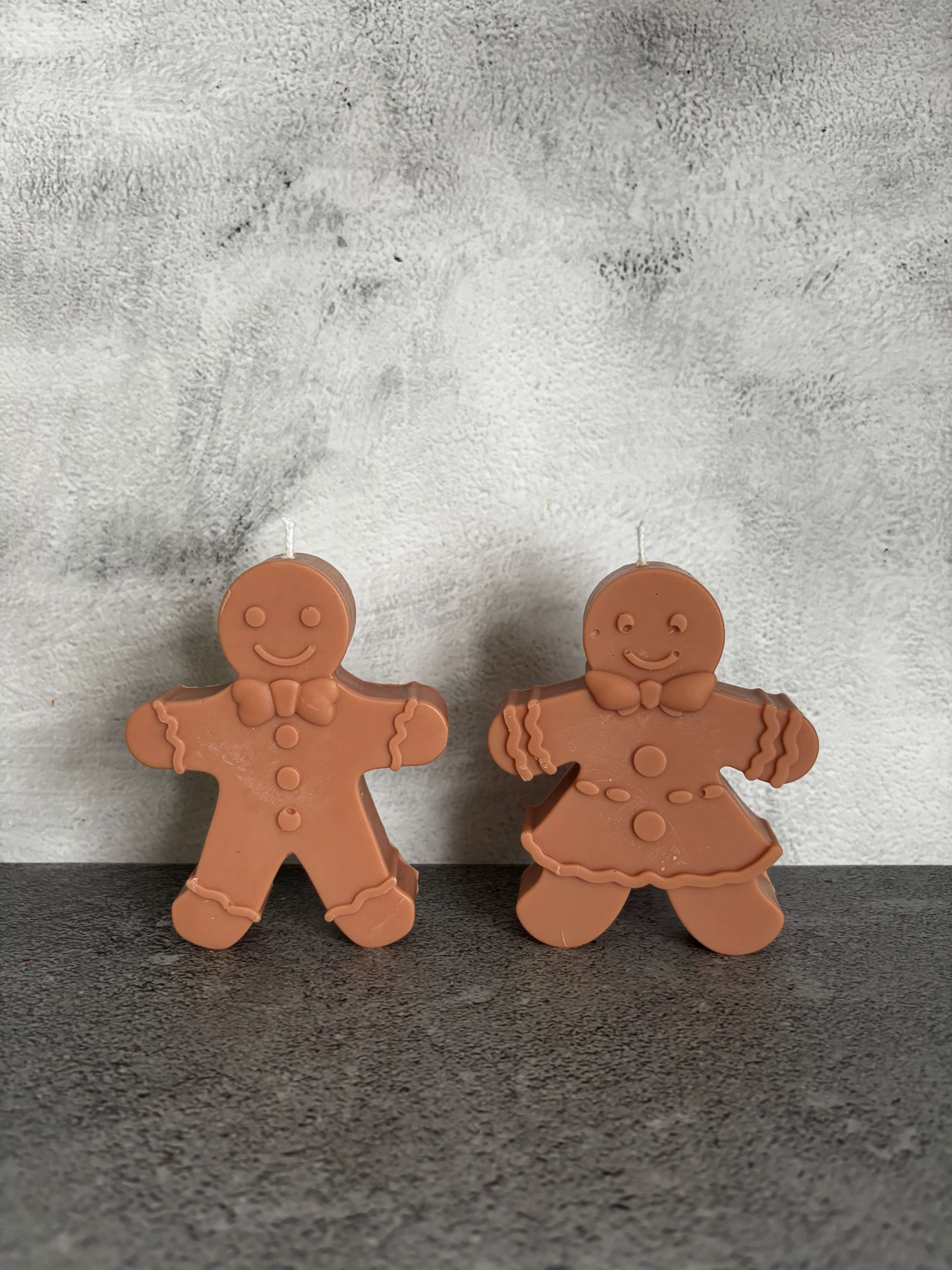 Two gingerbread-shaped cookies on a textured surface