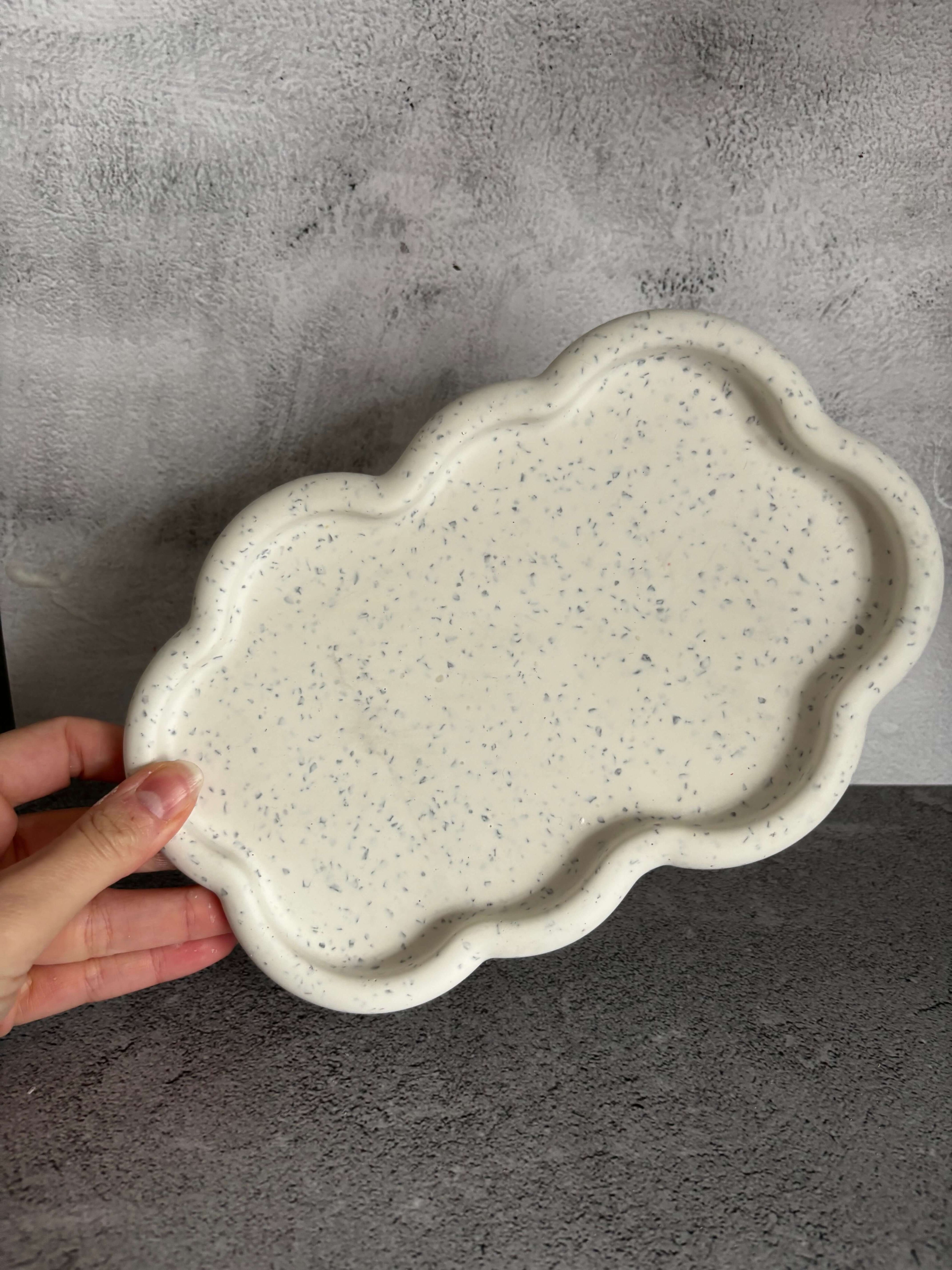 Hand holding a textured ceramic plate on a gray surface