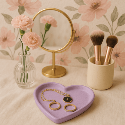 Jewellery set on a heart-shaped purple tray with makeup brushes in a holder, flowers, and a mirror on a floral background.