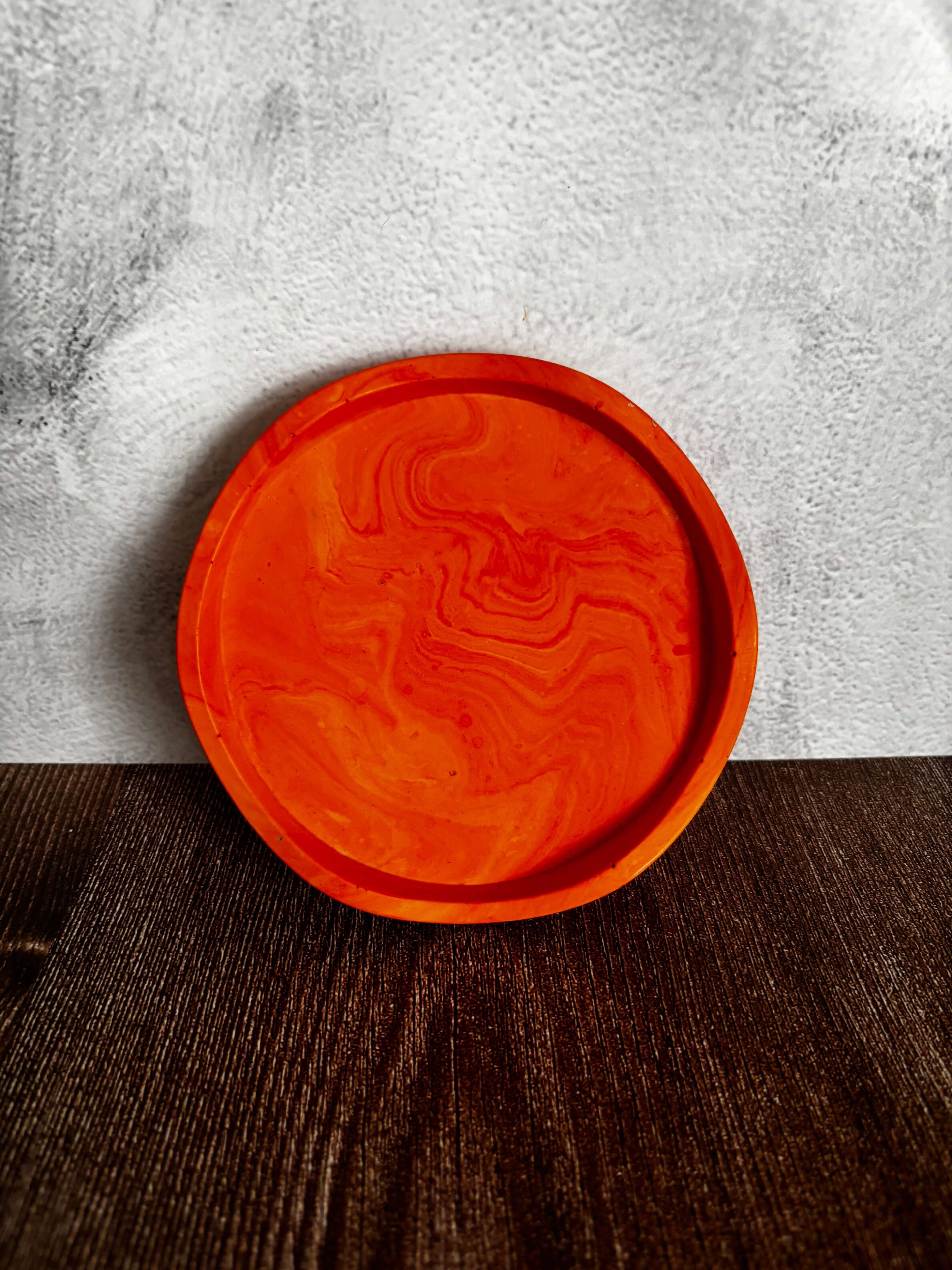 Orange round tray on a gray and wooden surface