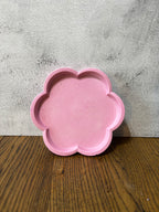 Pink flower-shaped object on a gray and wooden surface