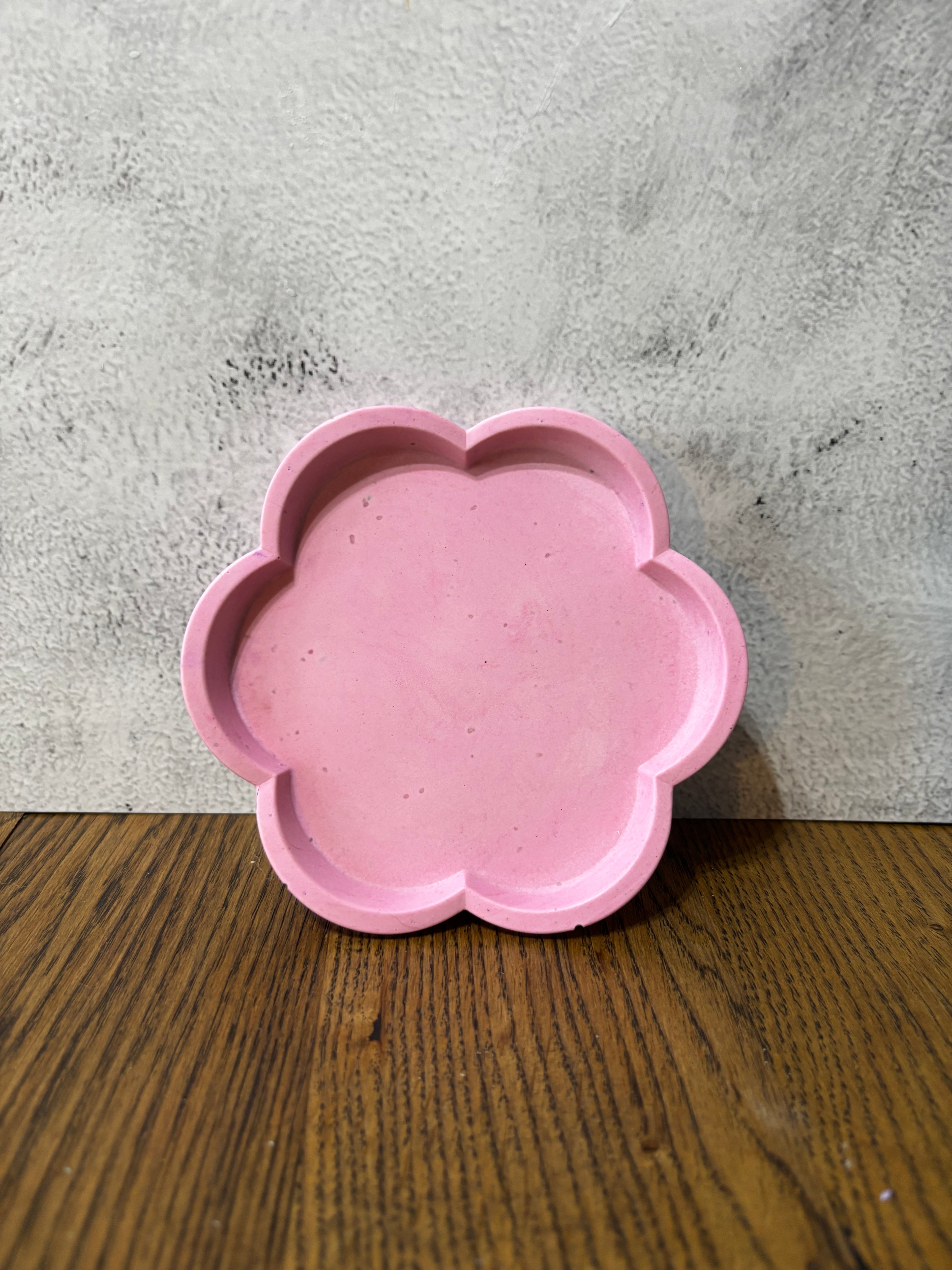 Pink flower-shaped object on a gray and wooden surface