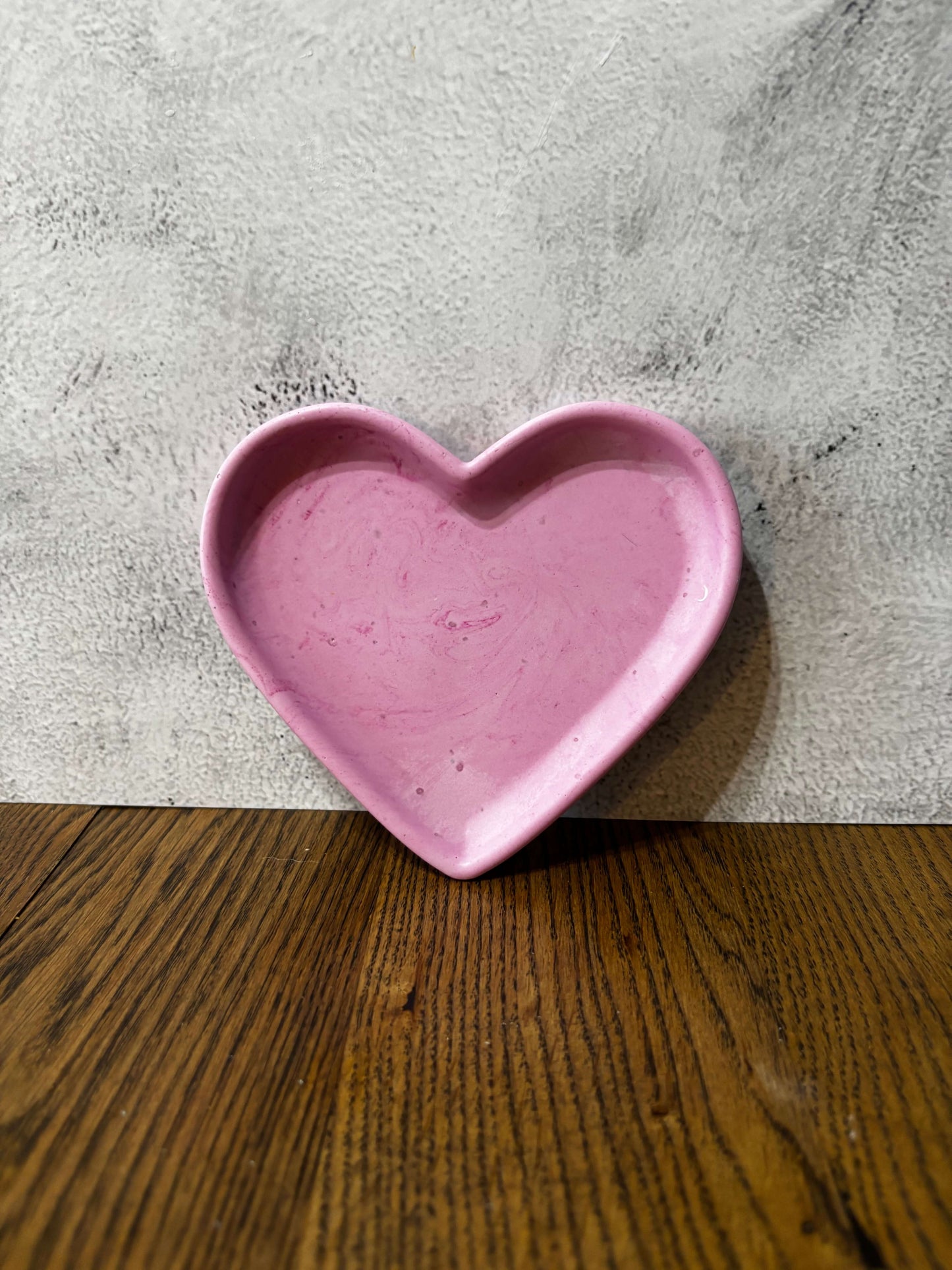 Pink heart-shaped dish on a textured surface with a wooden background