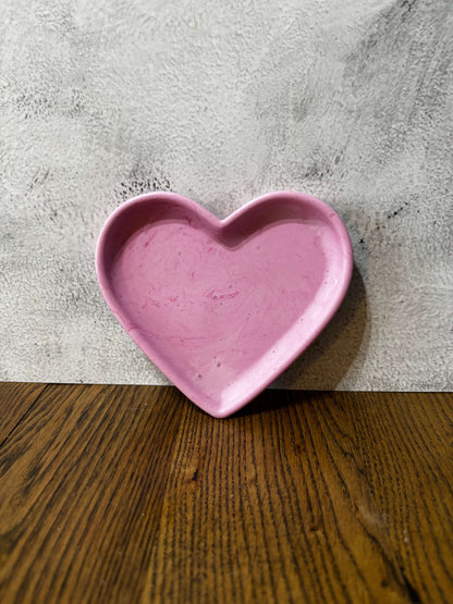 Pink heart-shaped dish on a textured surface with a wooden background