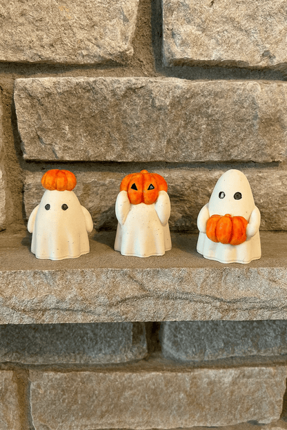 Three Halloween-themed figurines with pumpkins on a stone surface