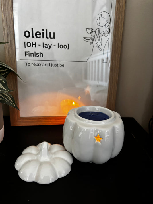 White decorative pumpkin with a star on top next to a framed picture with text.