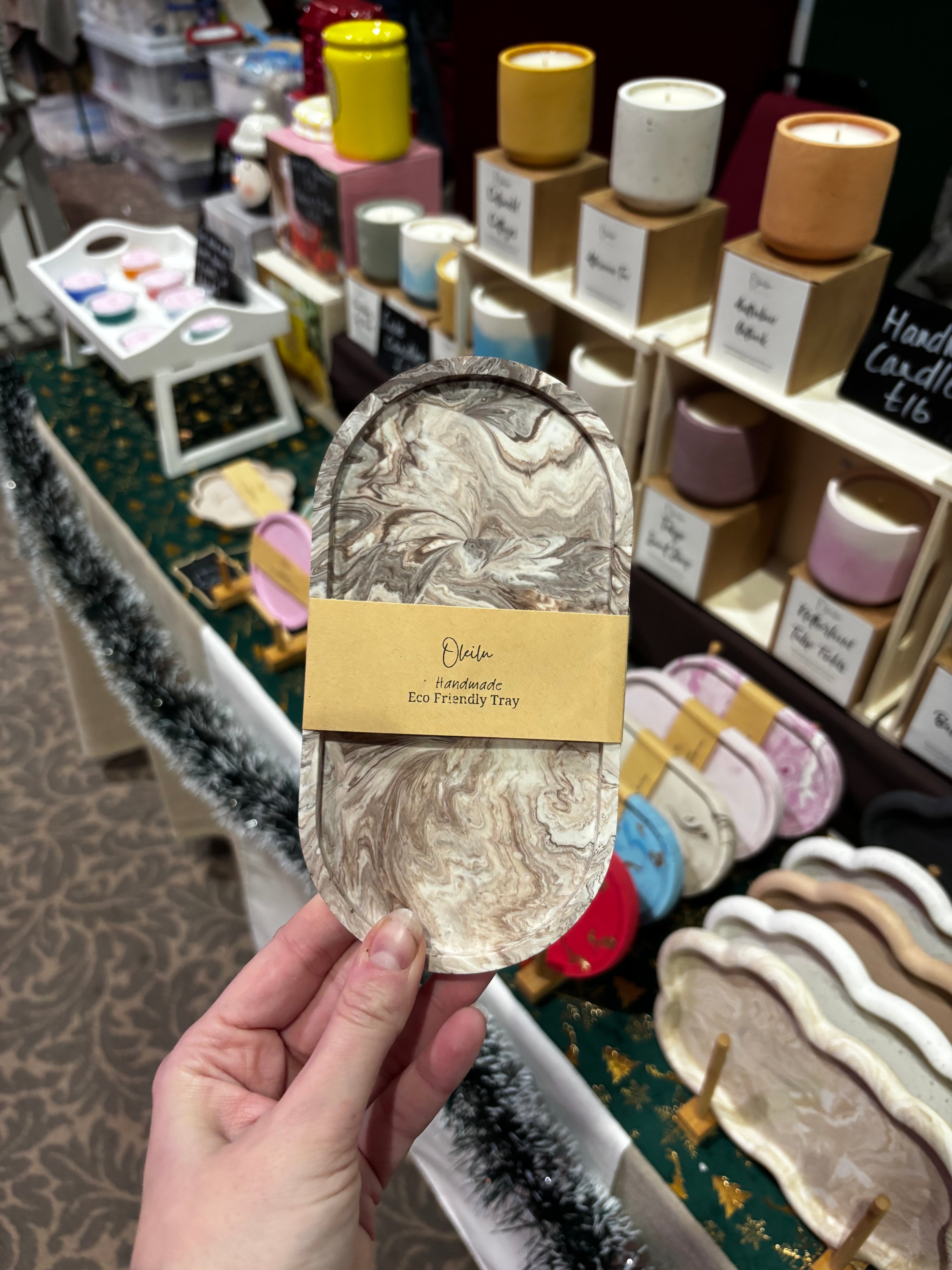 Handmade tray with decorative packaging held by a hand in a store setting.