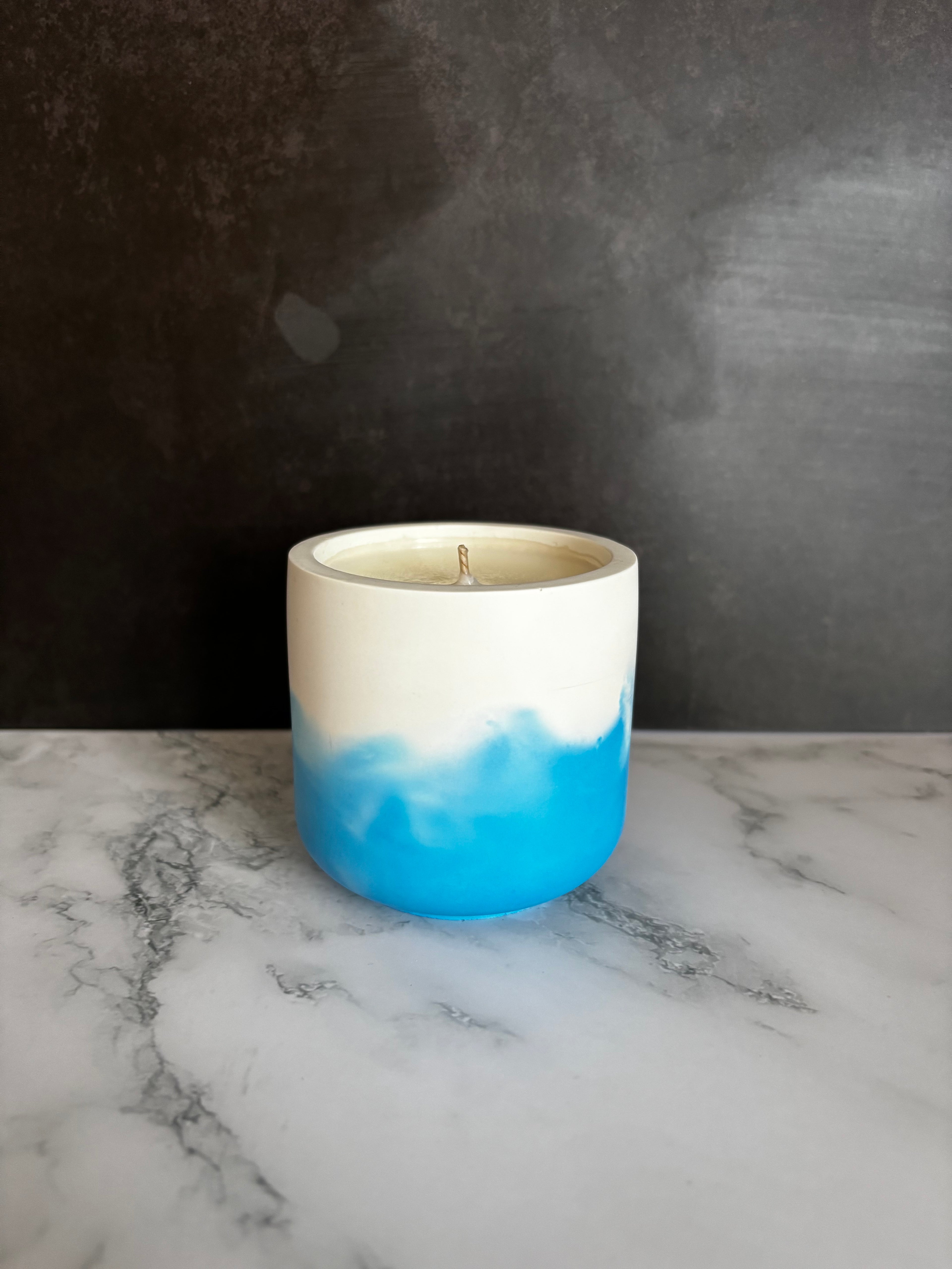 Cylindrical container with blue and white gradient on a dark surface and marble background