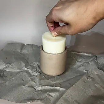 Hand placing a soy wax refill into a candle vessel, ready for use. Clean vessel for optimal burn time.